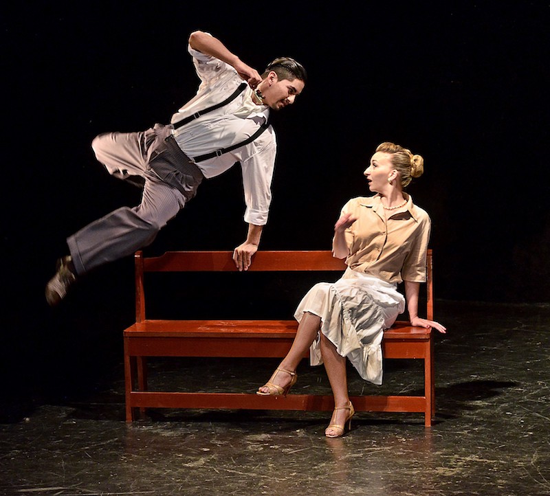 A woman sits on a bench and looks surprised as a man leaps over it